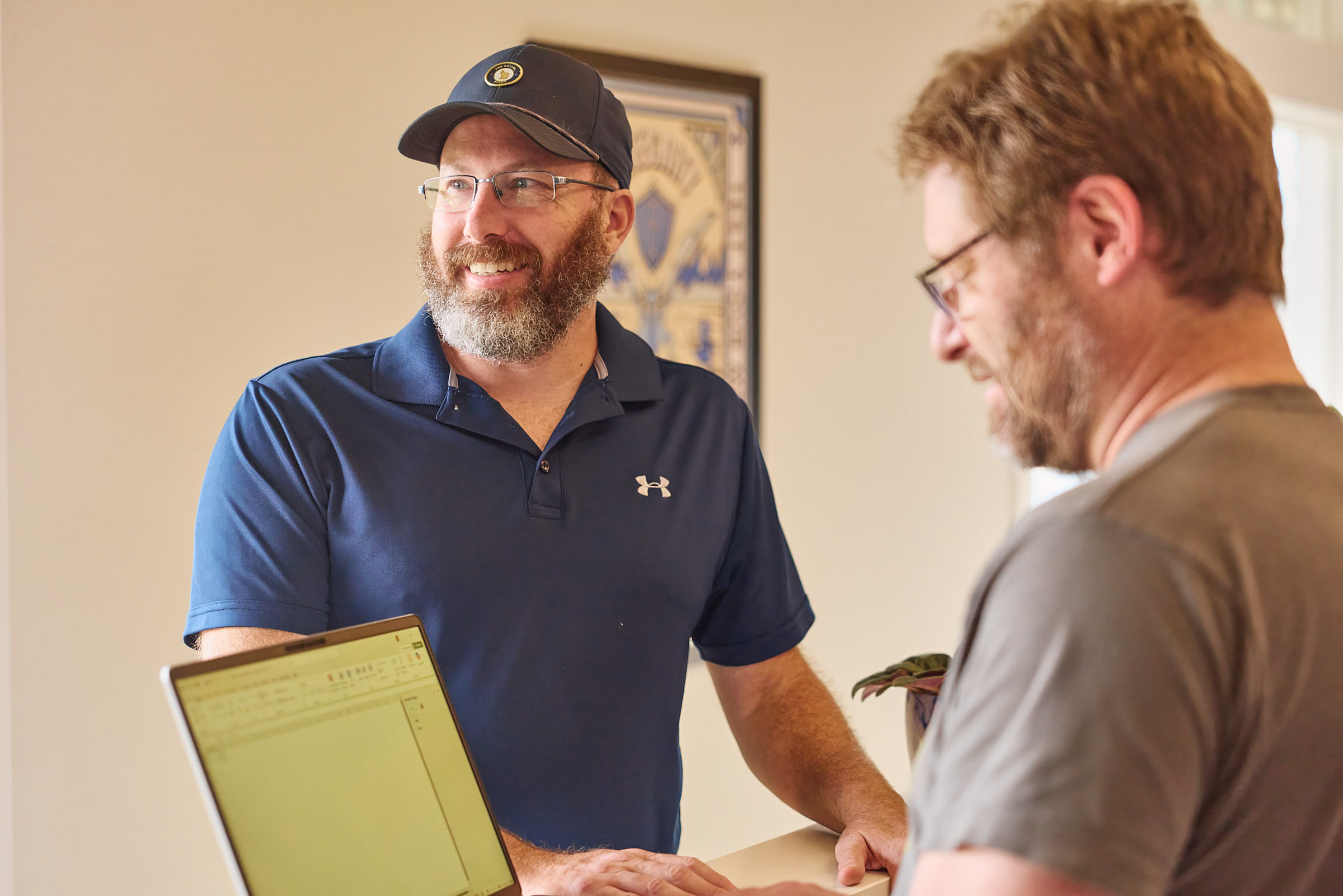 Two Mostly Serious team members discussing work beside a laptop.