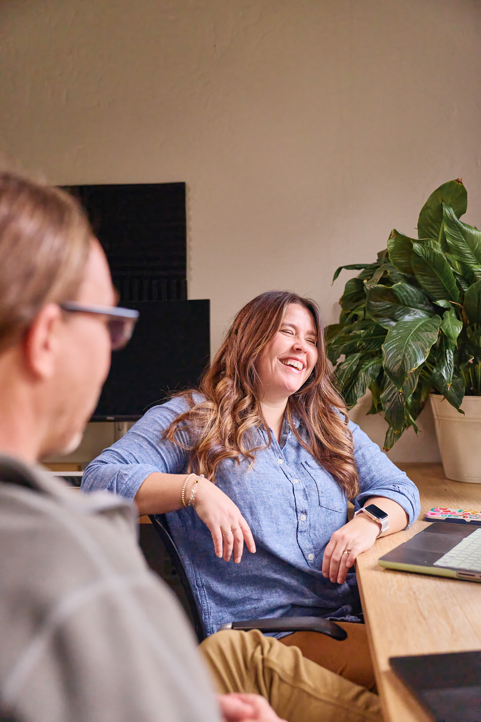 Two Mostly Serious team members laughing together during a meeting.