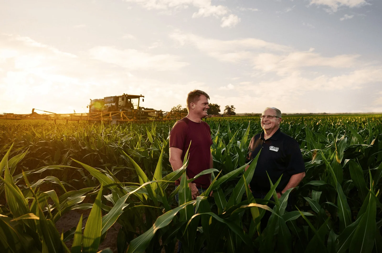 Two people standing in a field at sunset.