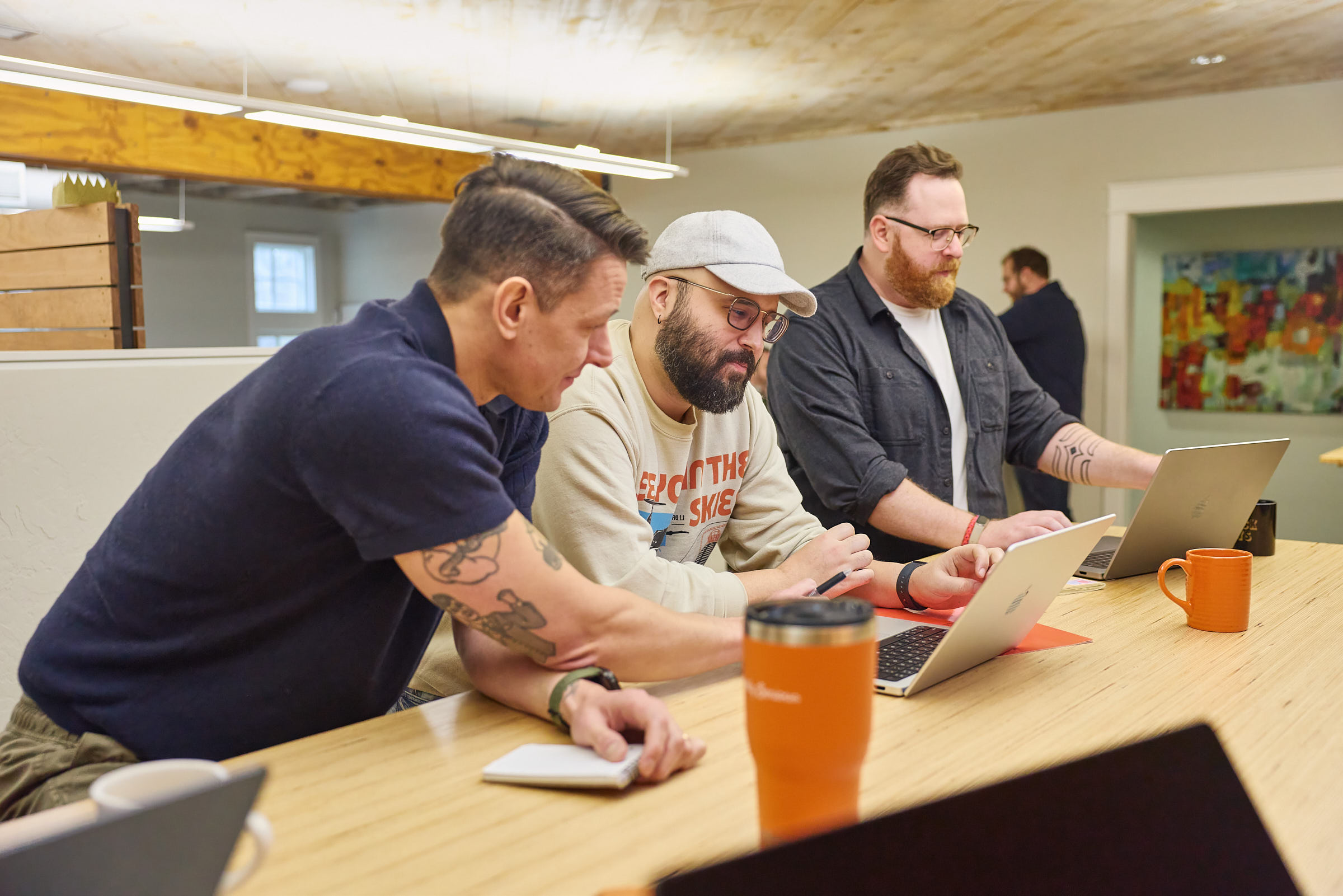 Three Mostly Serious team members working together at a standing table.