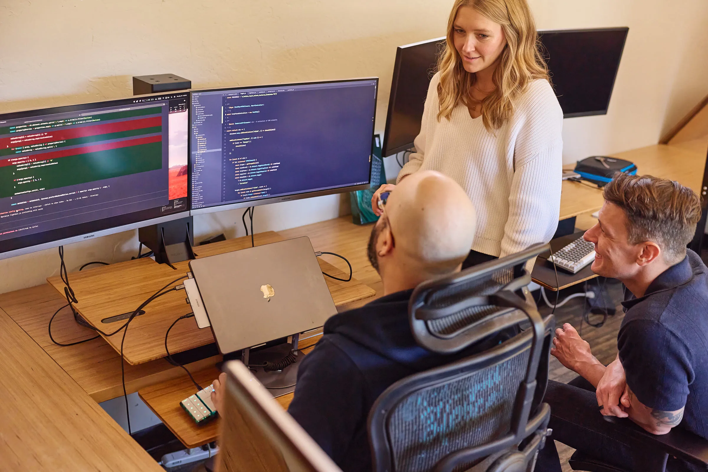 Three Mostly Serious team members collaborating around a workstation.